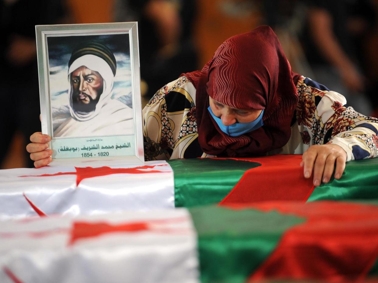 An Algerian woman holds a drawing of a fighter as she mourns over one of the coffins containing the remains of 24 Algerian resistance fighters: EPA/STRINGER