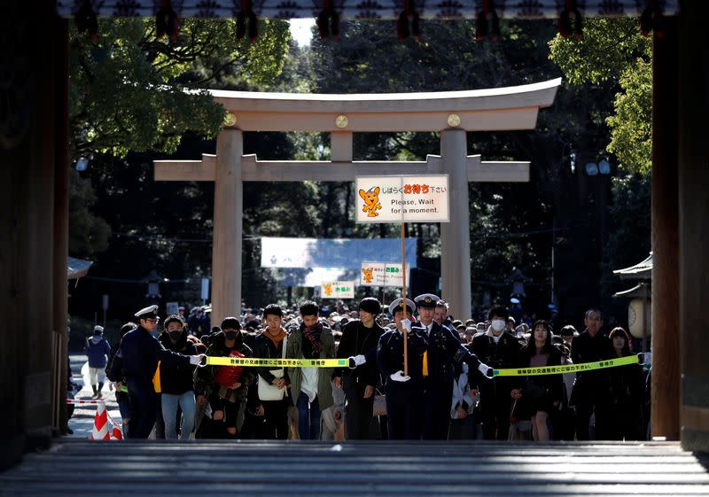 Police officers try to control as people make their way to offer prayers on the first day of the new year at the Meiji Shrine in Tokyo