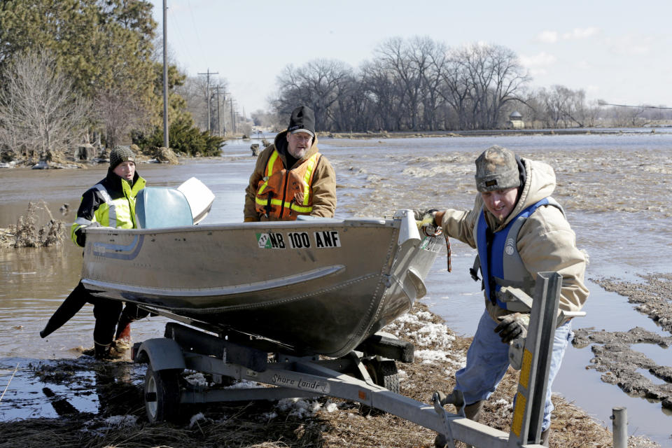 RETRANSMISSION TO CORRECT SURNAME - Tom Wilke, center, his son Chad, right, and Nick Kenny, load a boat out of the swollen waters of the North Fork of the Elkhorn River after checking on the Witke's flooded property, in Norfolk, Neb., Friday, March 15, 2019. Heavy rain falling atop deeply frozen ground has prompted evacuations along swollen rivers in Wisconsin, Nebraska and other Midwestern states. Thousands of people have been urged to evacuate along eastern Nebraska rivers as a massive late-winter storm has pushed streams and rivers out of their banks throughout the Midwest. (AP Photo/Nati Harnik)