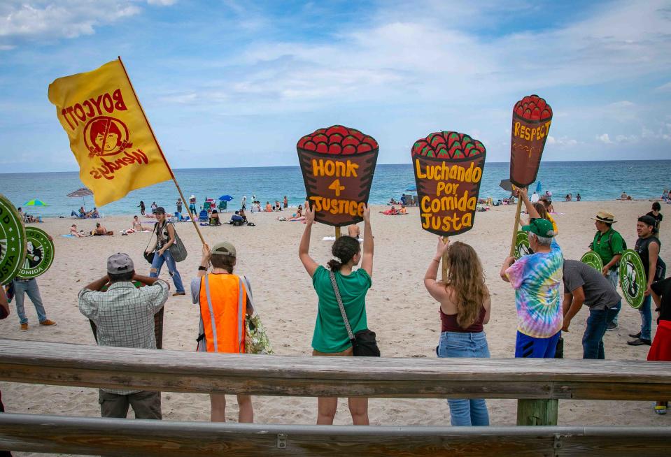 People hold signs and participate in a rally at Midtown Beach on Friday, the first of a three-day Farmworkers Festival.