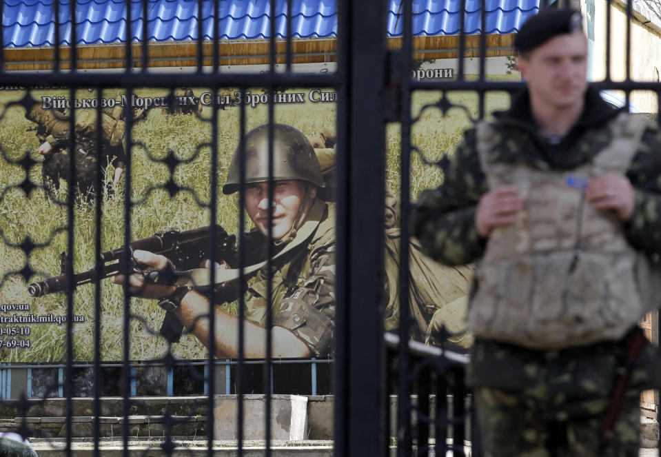 A Ukrainian soldier stands guard at the gate of a military base in the port of Kerch, Ukraine, Monday, March 3, 2014. Pro-Russian troops controlled a ferry terminal on the easternmost tip of Ukraine's Crimea region close to Russia on Monday, intensifying fears that Moscow will send even more troops into the strategic Black Sea region in its tense dispute with its Slavic neighbor. (AP Photo/Darko Vojinovic)