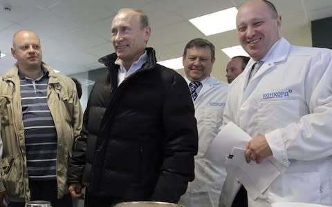 Yevgeny Prigozhin, right, smiles as he shows Russian President Vladimir Putin around his school meals factory which outside St Petersburg, Russia, in 2010 - Credit: AP