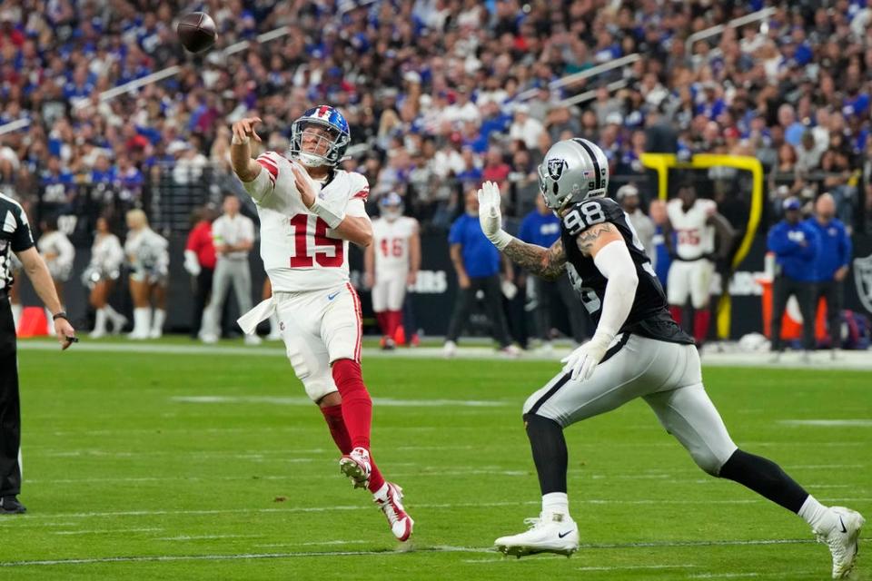 New York Giants quarterback Tommy DeVito (15) throws a touchdown pass as Las Vegas Raiders defensive end Maxx Crosby (98) defends during the second half of an NFL football game, Sunday, Nov. 5, 2023, in Las Vegas. (AP Photo/Rick Scuteri)