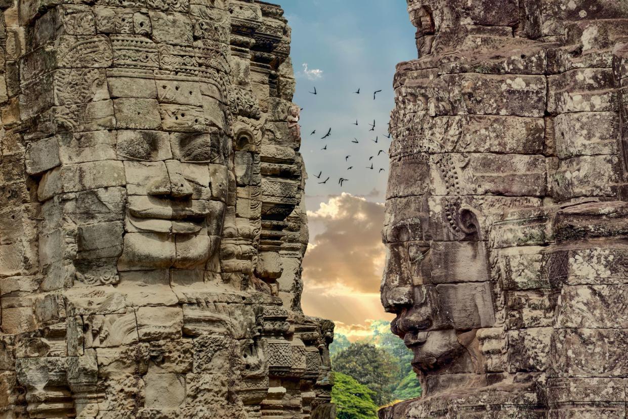 Faces of Bayon Temple, Angkor Thom, Cambodia with bird flying and sun rising