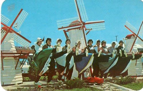 Dancers pose for a photo in front of the iconic windmills at Holland's Wooden Shoe Factory and Restaurant off U.S.-31.