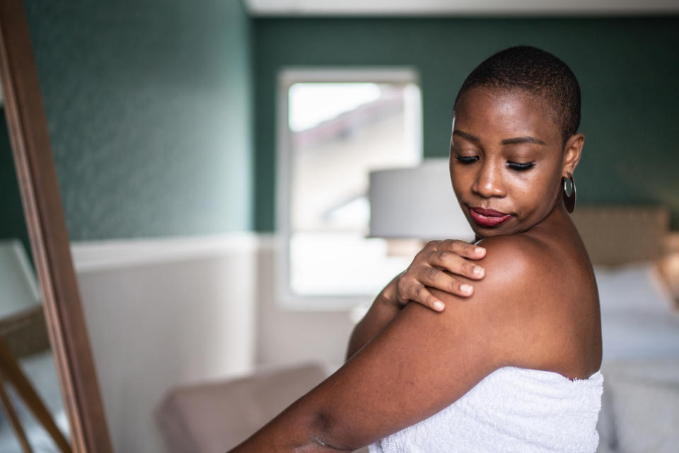 A woman rubbing her arm and looking at her shoulder