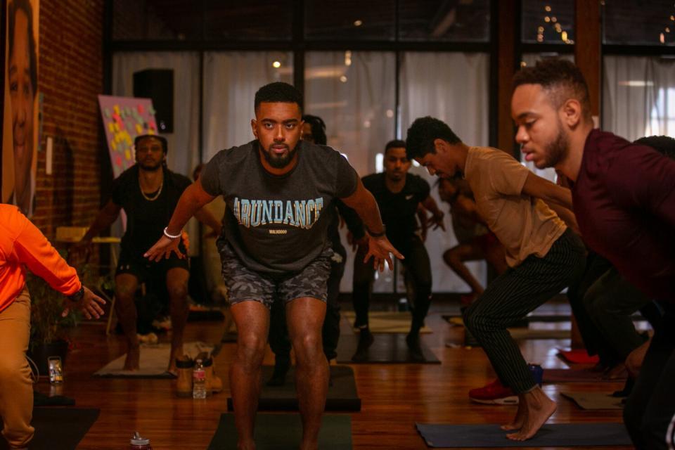 Several men participates in yoga in a room.