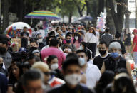 Families walk along Mexico City's Reforma Avenue during Day of the Dead celebrations, Sunday, Oct. 18, 2020. (AP Photo/Eduardo Verdugo)