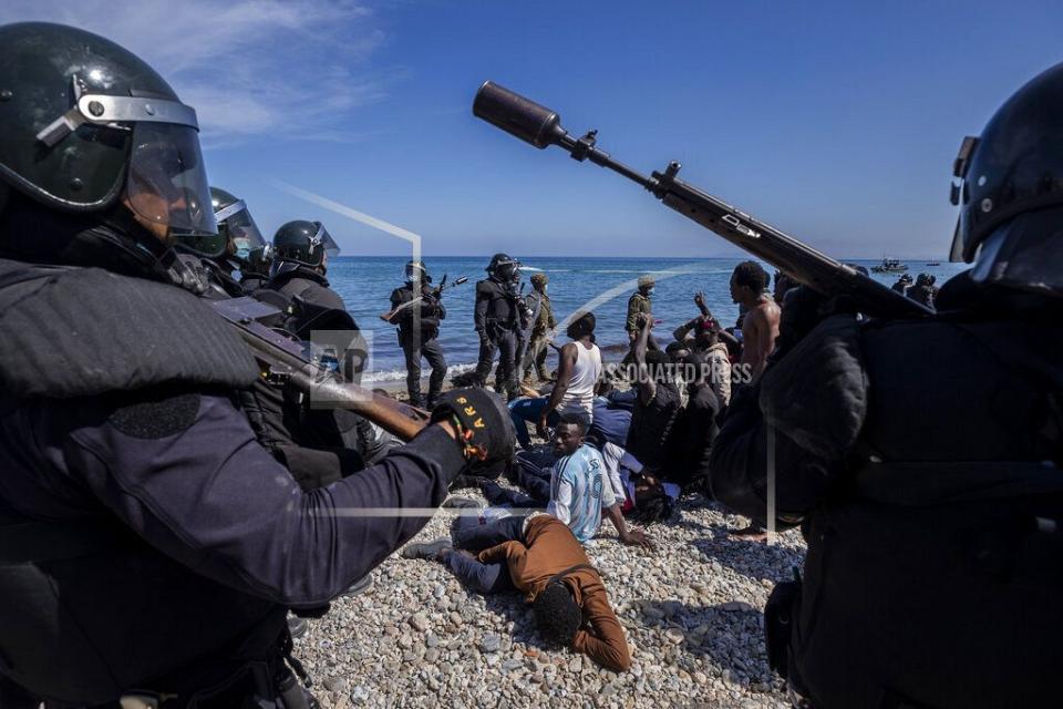 Migranti circondati dalla polizia spagnola vicino al confine tra Marocco e Spagna, nell'enclave spagnola di Ceuta, martedì 18 maggio 2021.