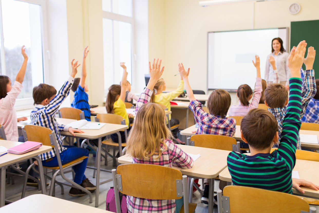 Kids raising their hands in a classroom