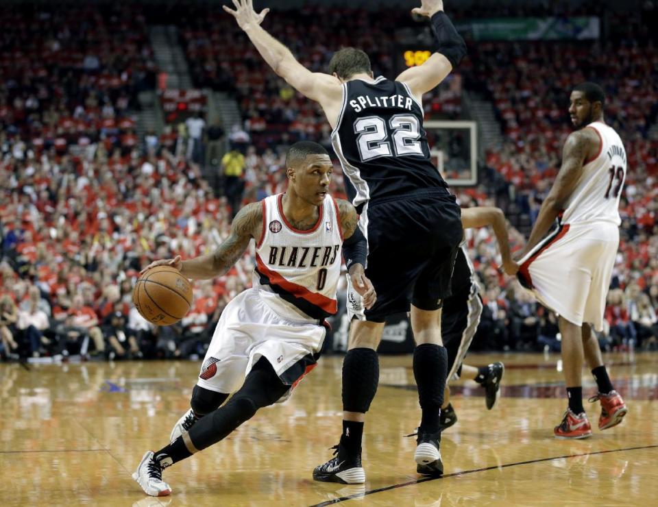 Portland Trail Blazers' Damian Lillard (0) drives around San Antonio Spurs' Tiago Splitter (22) in the second quarter during Game 3 of a Western Conference semifinal NBA basketball playoff series, Saturday, May 10, 2014, in Portland, Ore. (AP Photo/Rick Bowmer)