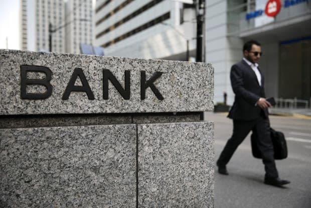 A pedestrian passes in front of a bank in the financial district of Toronto in July 2019. 