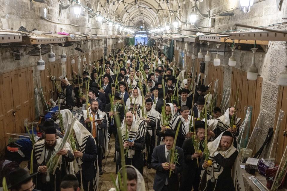 Jewish worshippers pray during the weeklong Jewish holiday of Sukkot, next to one of the gates to the Temple Mount, known to Muslims as the Noble Sanctuary, or the Al-Aqsa Mosque compound, in the Old City of Jerusalem, Wednesday, Oct. 4, 2023. (AP Photo/Ohad Zwigenberg)