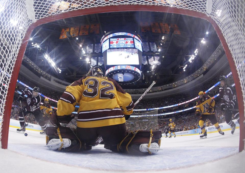 In this photo taken with a fisheye lens, Union's Eli Lichtenwald, left, heads towards Minnesota's Adam Wilcox, center, with the puck on his way to making a goal during the first period of an NCAA men's college hockey Frozen Four tournament game on Saturday, April 12, 2014, in Philadelphia. (AP Photo/Chris Szagola)