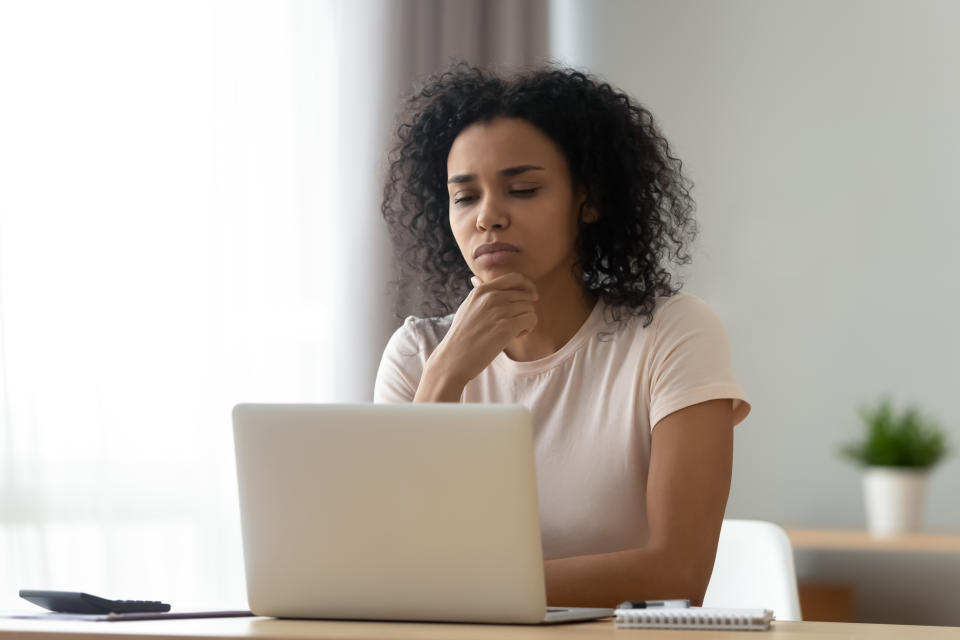 Pensive african American young woman sit at desk thinking studying or working on laptop at home, thoughtful black millennial girl student pondering considering idea looking at computer screen