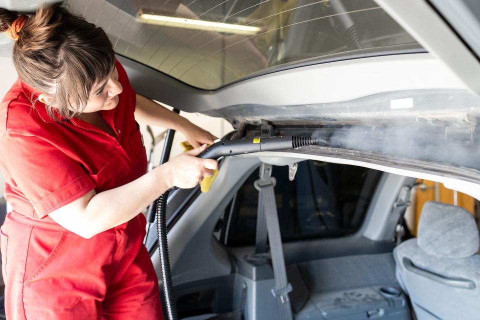 woman steam cleaning car crevice