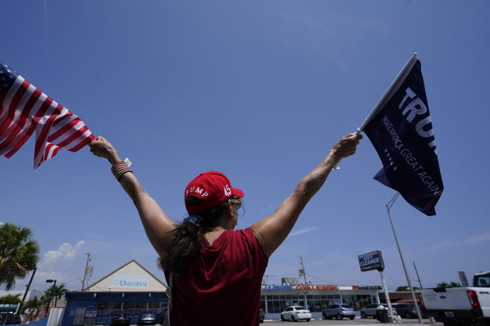 A supporter of former President Donald Trump waves flags Monday, April 3, 2023, in West Palm Beach, Fla. Trump is expected to travel to New York for his booking and arraignment on charges arising from hush money payments during his 2016 campaign. (AP Photo/Wilfredo Lee)