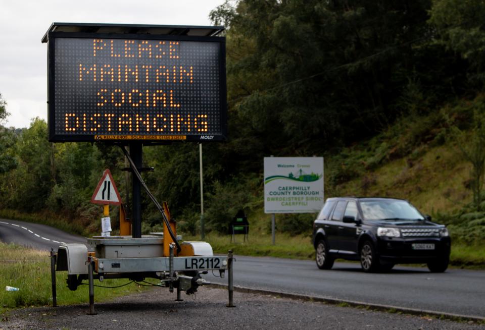 HOLLYBUSH, CAERPHILLY, WALES - SEPTEMBER 10:  A general view of a solar powered social distancing reminder sign which has been placed on the entry to Caerphilly Borough, where people are not allowed to enter or leave the Borough unless it is an essential journey, on September 10, 2020 in Hollybush, Wales, United Kingdom. The county borough of Caerphilly in South Wales is to be placed under a local lockdown from 18:00 BST on Tuesday, following a rapid rise in cases of coronavirus, in the first local lockdown in Wales. People will not be able to leave the borough without good reason and face masks will be required by everyone aged over 11 in shops. Seeing others within extended households indoors will also be banned. The Welsh government have said that with 55.4 cases per 100,000 population, Caerphilly county has the highest rate in Wales and one of the highest in the UK. (Photo by Huw Fairclough/Getty Images)