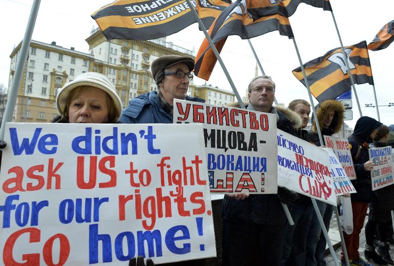 People hold placards during a protest against US international policy in front of the US embassy (background) in central Moscow on March 7, 2015