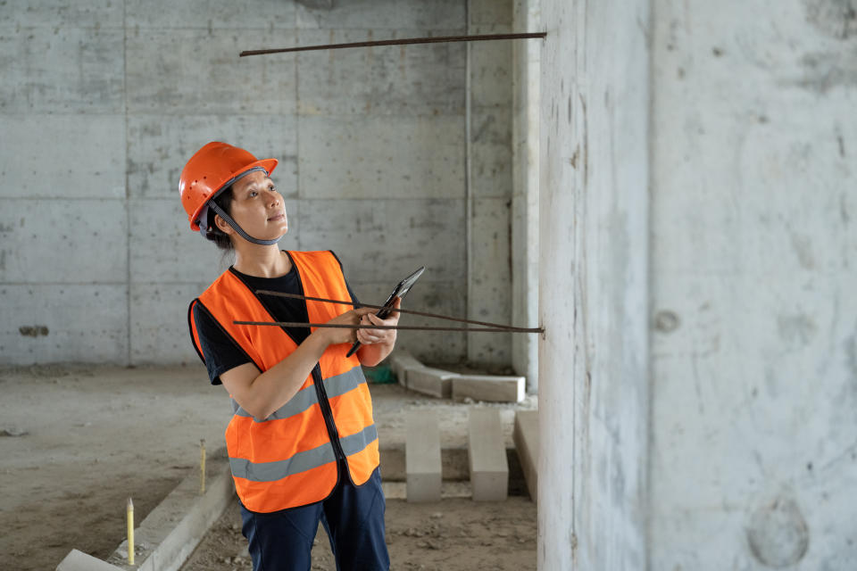 An Asian female engineer inspects the quality of a commercial building construction site under construction