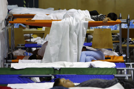 Asylum seekers from various countries sleep as they wait to be registered inside a hall, used by German police as the first registration point, in Passau, Germany July 29, 2015. REUTERS/Michaela Rehle