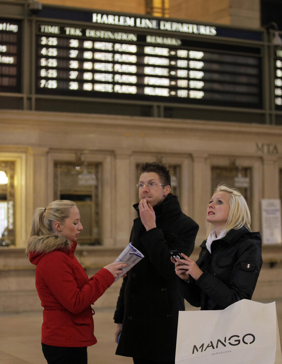 Three people consult a Metro-North commuter railroad time table near the ticket windows in New York's Grand Central Terminal, Wednesday, Oct. 31, 2012. People in the coastal corridor battered by superstorm Sandy took the first cautious steps Wednesday to reclaim routines upended by the disaster, even as rescuers combed neighborhoods strewn with debris and scarred by floods and fire. (AP Photo/Richard Drew)