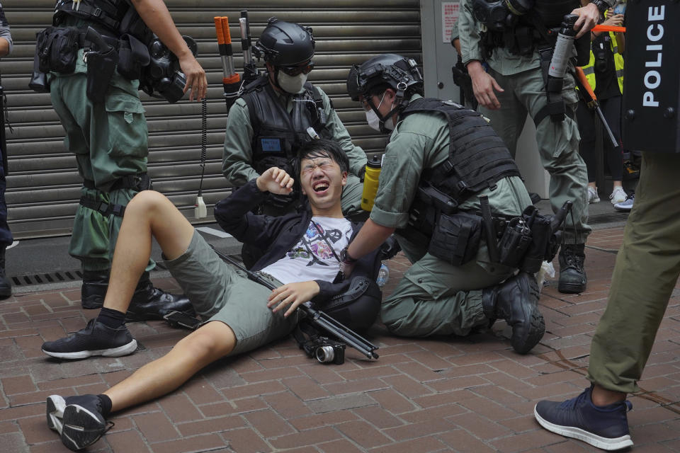 A reporter falls down after being sprayed with pepper spray by police during a protest in Causeway Bay during the annual handover march in Hong Kong, Wednesday, July. 1, 2020. Hong Kong marked the 23rd anniversary of its handover to China in 1997, and just one day after China enacted a national security law that cracks down on protests in the territory. (AP Photo/Vincent Yu)