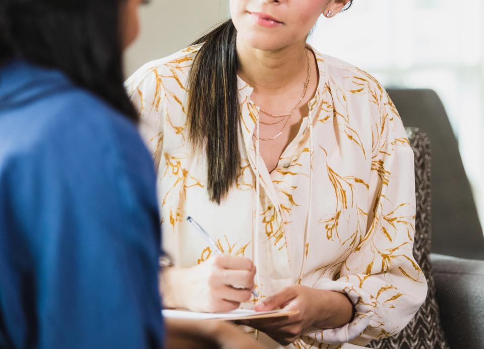 A woman takes notes during an interview with a visiting client