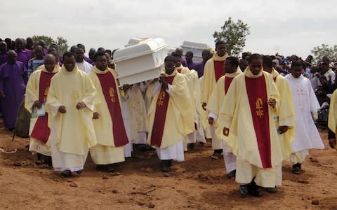 Clergymen carry white coffins containing the bodies of priests allegedly killed by Fulani herdsmen after clashes in May - Credit:  EMMY IBU/AFP