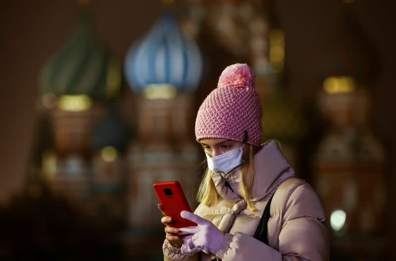 A woman uses her mobile phone before the opening of an outdoor skating rink in the Red Square in Moscow