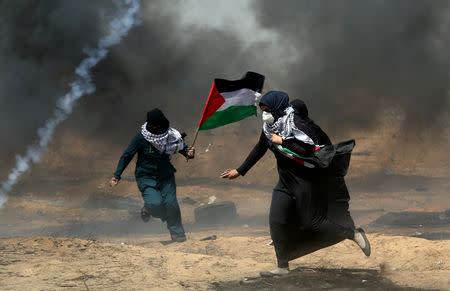 Female demonstrators run for cover from tear gas fired by Israeli forces during a protest where Palestinians demanded the right to return to their homeland, at the Israel-Gaza border in the southern Gaza Strip, May 11, 2018. REUTERS/Ibraheem Abu Mustafa