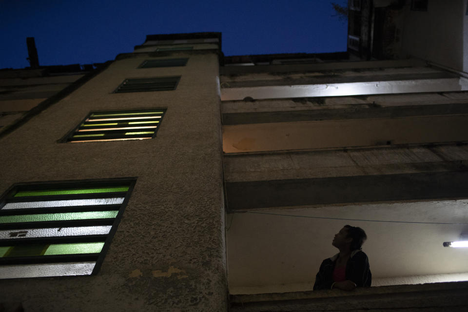 A resident looks up from her balcony at the squat known as Casa Nem, occupied by members of the LGBTQ community who are in self-quarantine as a protective measure against the new coronavirus, in Rio de Janeiro, Brazil, Friday, May 29, 2020. New residents during the pandemic have to isolate on one of the building's floors for 15 days to ensure they don’t develop symptoms before fully joining the community. (AP Photo/Silvia Izquierdo)