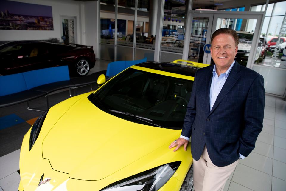 Keith McCluskey, McCluskey Chevrolet's CEO, stands next to a Corvette in the showroom.