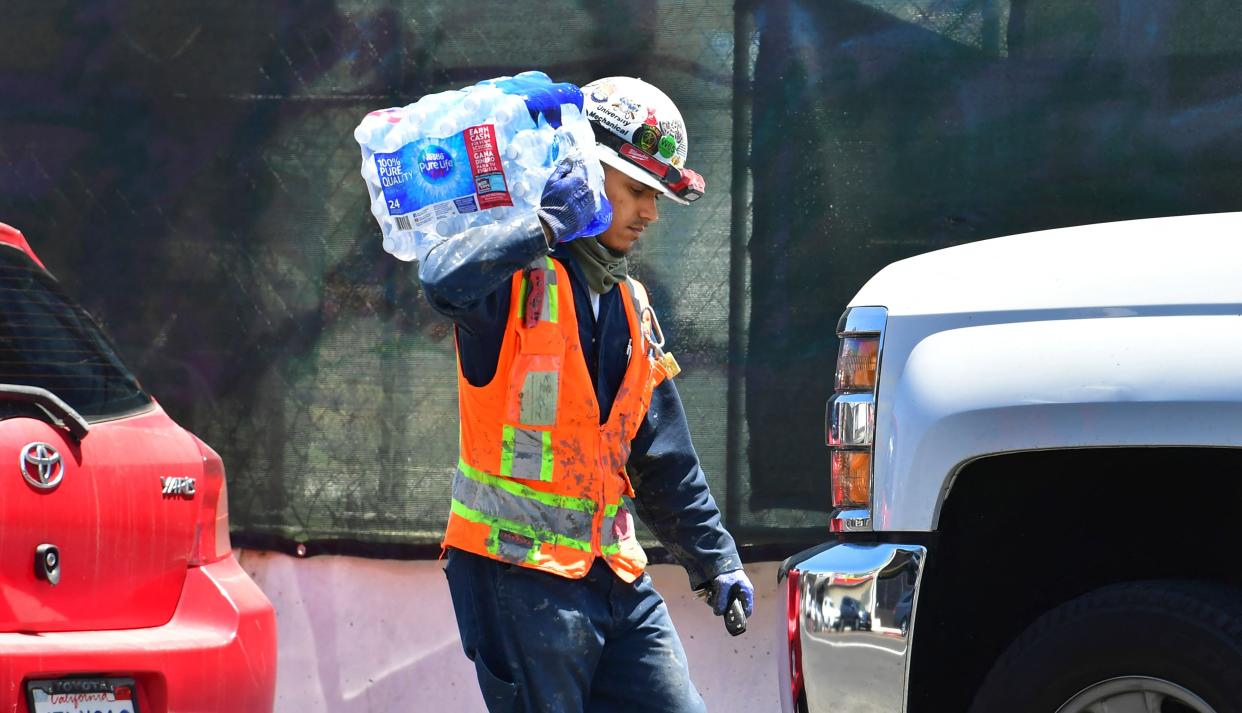 A construction worker carries a 24-pack of bottled water over his shoulder on June 14, 2021 in Los Angeles, where an early season heat wave is set to be in full swing this week across much of California (AFP via Getty Images)