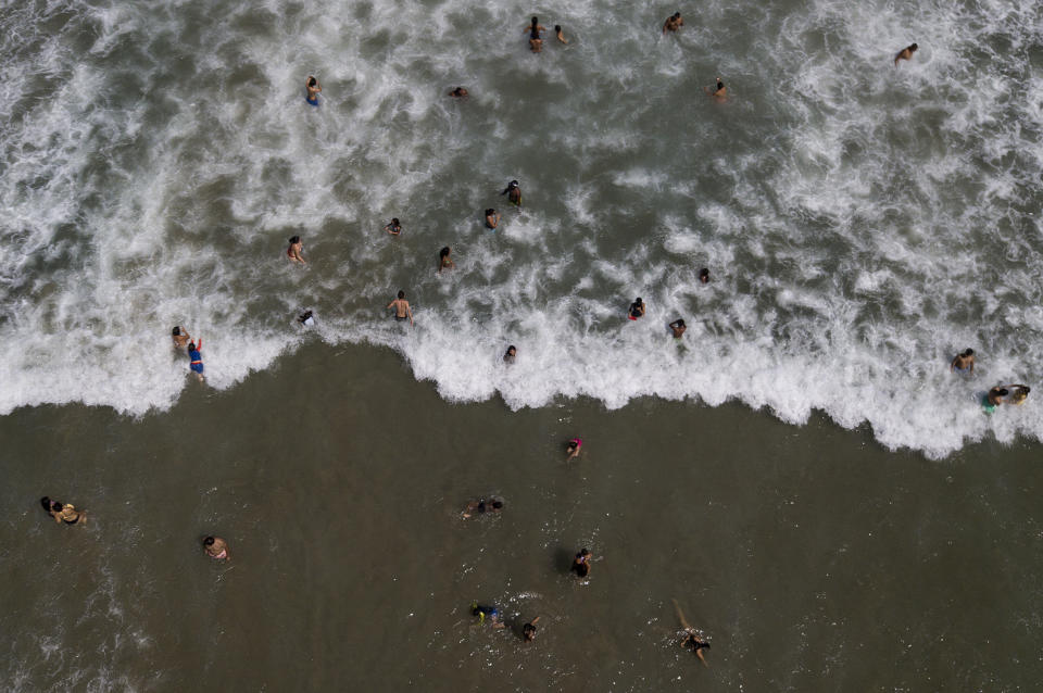La gente nada en la playa Los Ángeles después de su reciente reapertura después de una cuarentena para enfrentar la pandemia del nuevo coronavirus en La Guaira, Venezuela, el viernes 23 de octubre de 2020. (AP Foto/Matias Delacroix)