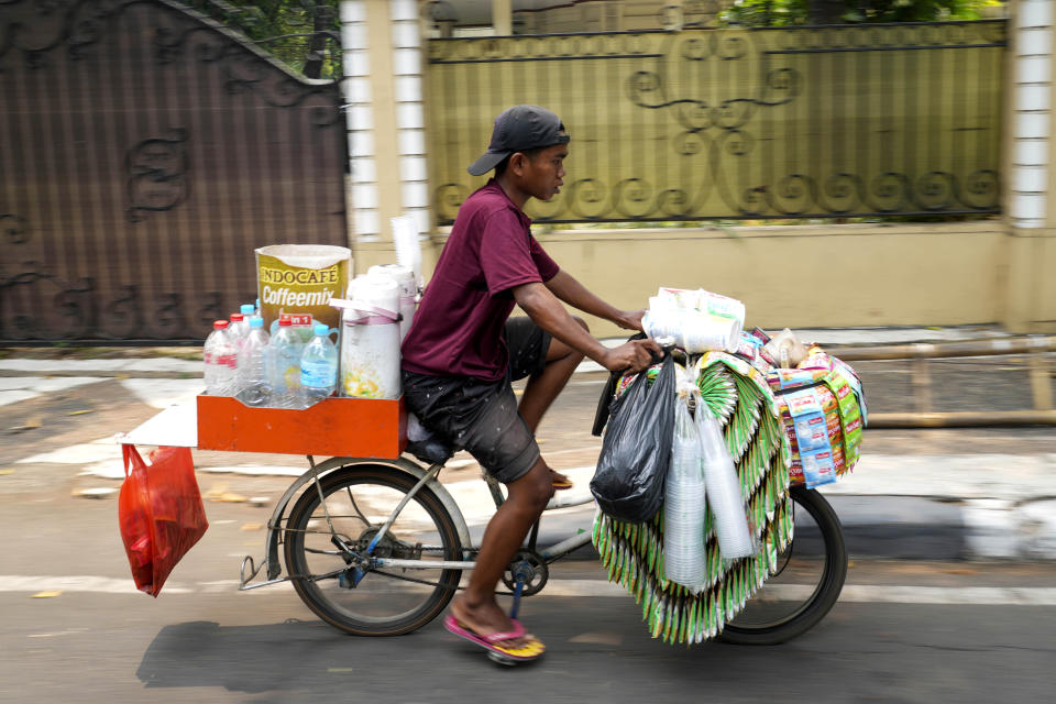 A snack and drink vendor carries his wares on a bike in Jakarta, Indonesia Tuesday, Oct. 24, 2023. Indonesia — the biggest sugar importer last year, according to the United States Department of Agriculture — has cut back on imports. (AP Photo/Tatan Syuflana)