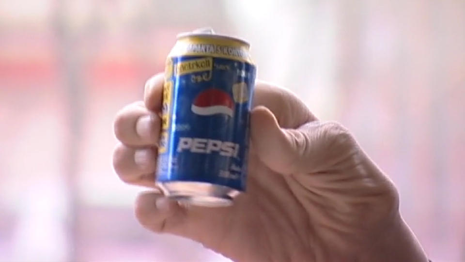 A giant hand holding a can of Pepsi