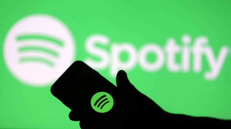 FILE PHOTO: A smartphone is seen in front of a screen projection of the Spotify logo in this picture illustration