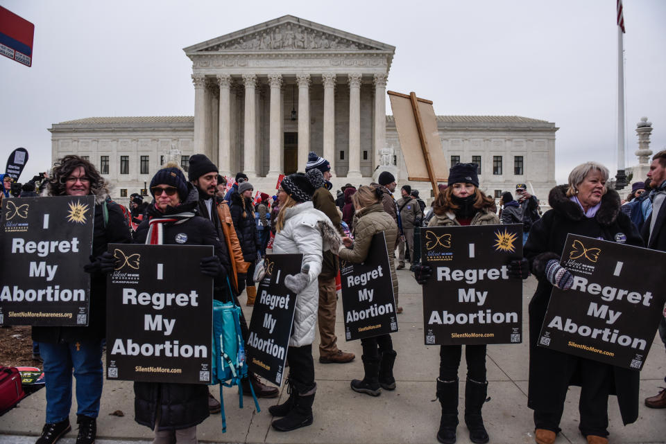 Demonstrators hold signs saying: I Regret My Abortion, in front of the U.S. Supreme Court.