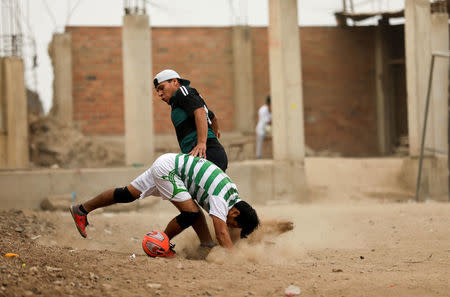 Men play soccer at a makeshift soccer field in Nueva Union shantytown in Villa Maria del Triunfo district of Lima, Peru, June 3, 2018. REUTERS/Mariana Bazo