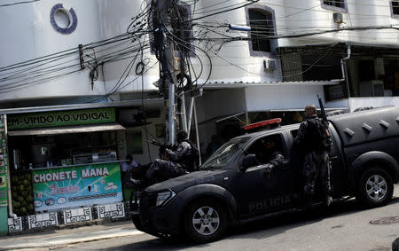 Police officers hang on to a car during an operation after clashes with drug dealers in Vidigal slum in Rio de Janeiro, Brazil August 14, 2018. Picture taken August 14, 2018. REUTERS/Ricardo Moraes