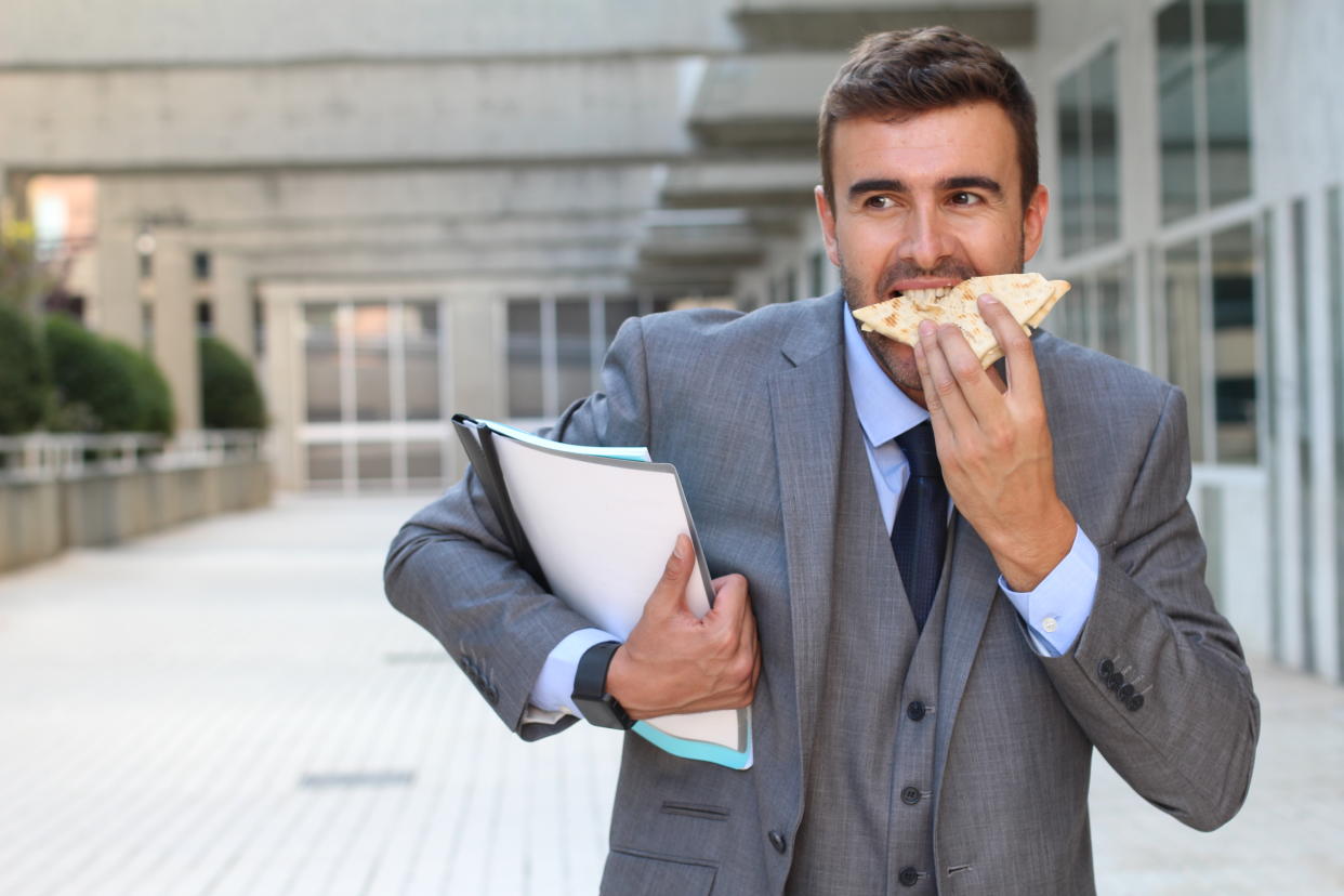 Businessman eating a sandwich on the go.