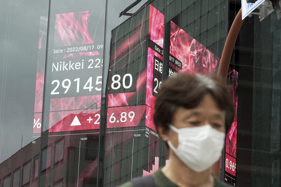 A person wearing a protective mask walks past an electronic stock board showing Japan's Nikkei 225 index at a securities firm Wednesday, Aug. 17, 2022, in Tokyo. Asian shares were mostly higher Wednesday as regional markets looked to strong economic signs out of the U.S. and China as drivers of growth. (AP Photo/Eugene Hoshiko)