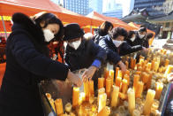 Parents place candles during a special service to wish for their children's success in the college entrance exams at the Jogyesa Buddhist temple in Seoul, South Korea, Thursday, Dec. 3, 2020. Hundreds of thousands of masked students in South Korea, including dozens of confirmed COVID-19 patients, took the highly competitive university entrance exam Thursday despite a viral resurgence that forced authorities to toughen social distancing rules. (AP Photo/Ahn Young-joon)