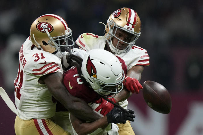 Arizona Cardinals wide receiver DeAndre Hopkins, center, loses control of the ball as he is hit by San Francisco 49ers cornerback Charvarius Ward, right, and safety Tashaun Gipson Sr. during the second half of an NFL football game Monday, Nov. 21, 2022, in Mexico City. (AP Photo/Fernando Llano)