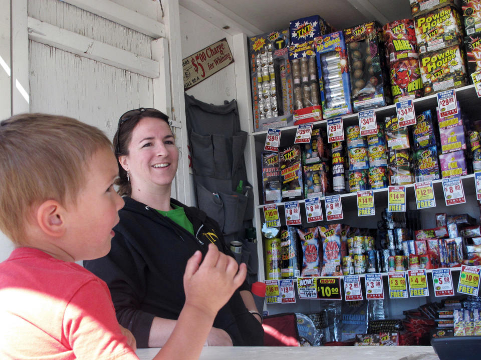 In this Thursday, June 28, 2012 photo, Clinton Kendall, 3, looks at fireworks for sale while the stand's owner, Anna Richards, looks on in Helena, Mont. Montana officials have urged people not to shoot fireworks while extreme wildfire conditions exist. (AP Photo/Matt Volz)