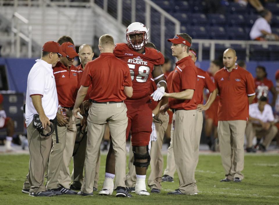 Florida Atlantic offensive lineman Reggie Bain is helped off the field during the second half of an NCAA college football game against Miami, in the early morning hours of, Saturday, Sept. 12, 2015, in Boca Raton, Fla. (AP Photo/Wilfredo Lee)