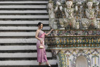 A Chinese tourist in traditional Thai dress poses for a photograph at Wat Arun or the "Temple of Dawn" in Bangkok, Thailand on Jan. 12, 2023. A hoped-for boom in Chinese tourism in Asia over next week’s Lunar New Year holidays looks set to be more of a blip as most travelers opt to stay inside China if they go anywhere. (AP Photo/Sakchai Lalit)