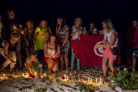 People place lit candles in the sand in front of the Imperial Marhaba Hotel, where a gunman had carried out an attack, in Sousse, Tunisia, June 28, 2015. REUTERS/Zohra Bensemra