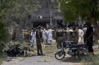 Police officers, investigators and rescue workers gather at the site of explosion, in Lahore, Pakistan, Wednesday, June 23, 2021. A powerful explosion ripped through a residential area in the eastern city of Lahore on Wednesday, killing some people and injuring some others, police and rescue officials said. (AP Photo/K.M. Chaudary)